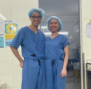 Two surgeons stand in blue scrubs ready for surgery.